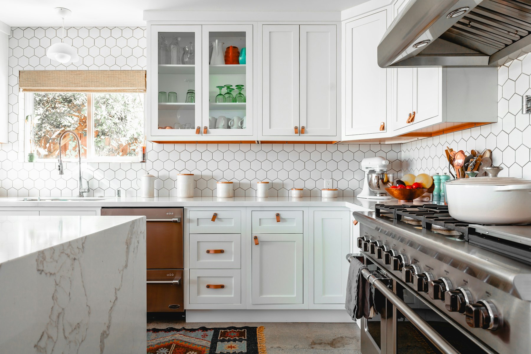 A working kitchen — white cabinetry, hexagonal tile, steel range