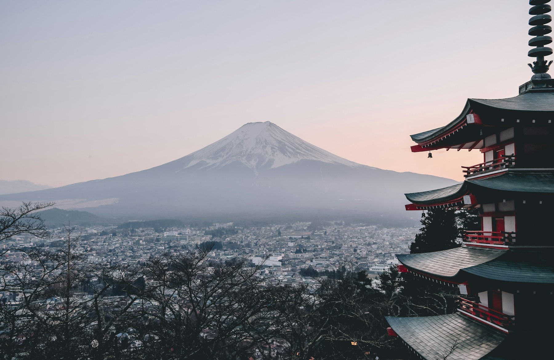 Mount Fuji rising through morning mist beyond a red five-storey pagoda