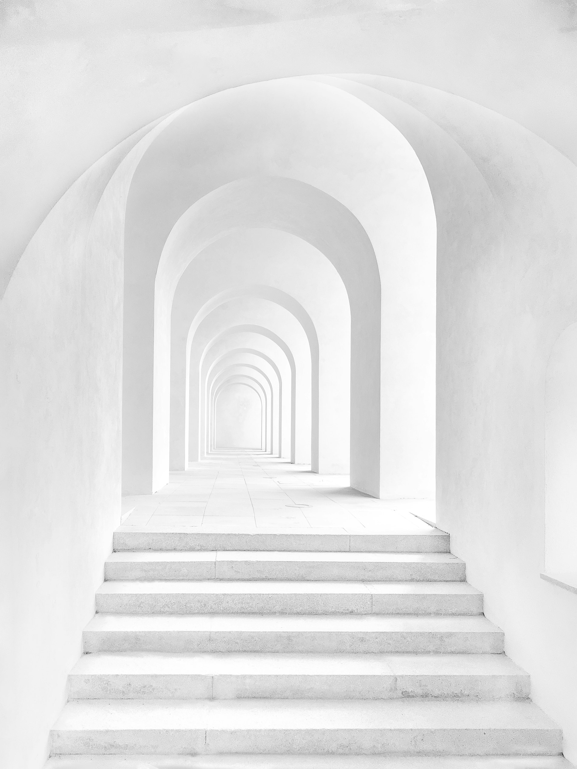 An arched corridor in pale stone, ascending
